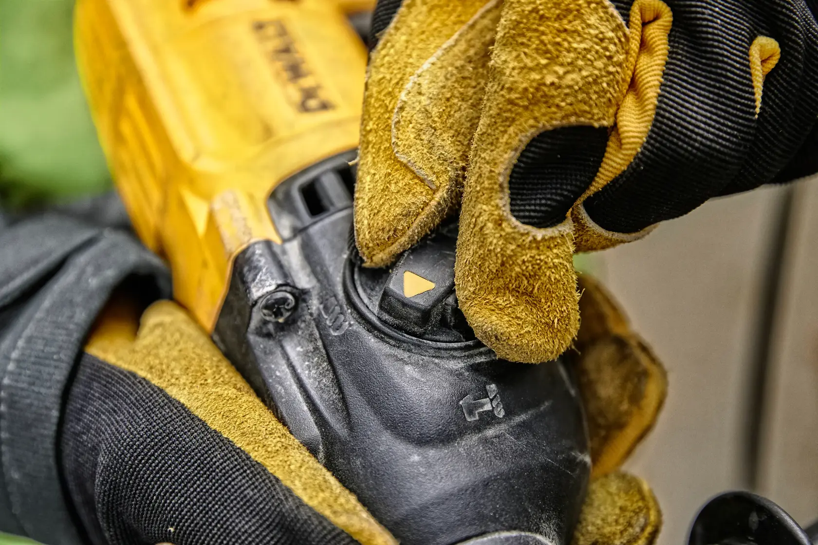 Close-up de uma pessoa usando luvas de trabalho amarelas e pretas ajustando o seletor de modo em uma ferramenta elétrica DEWALT.