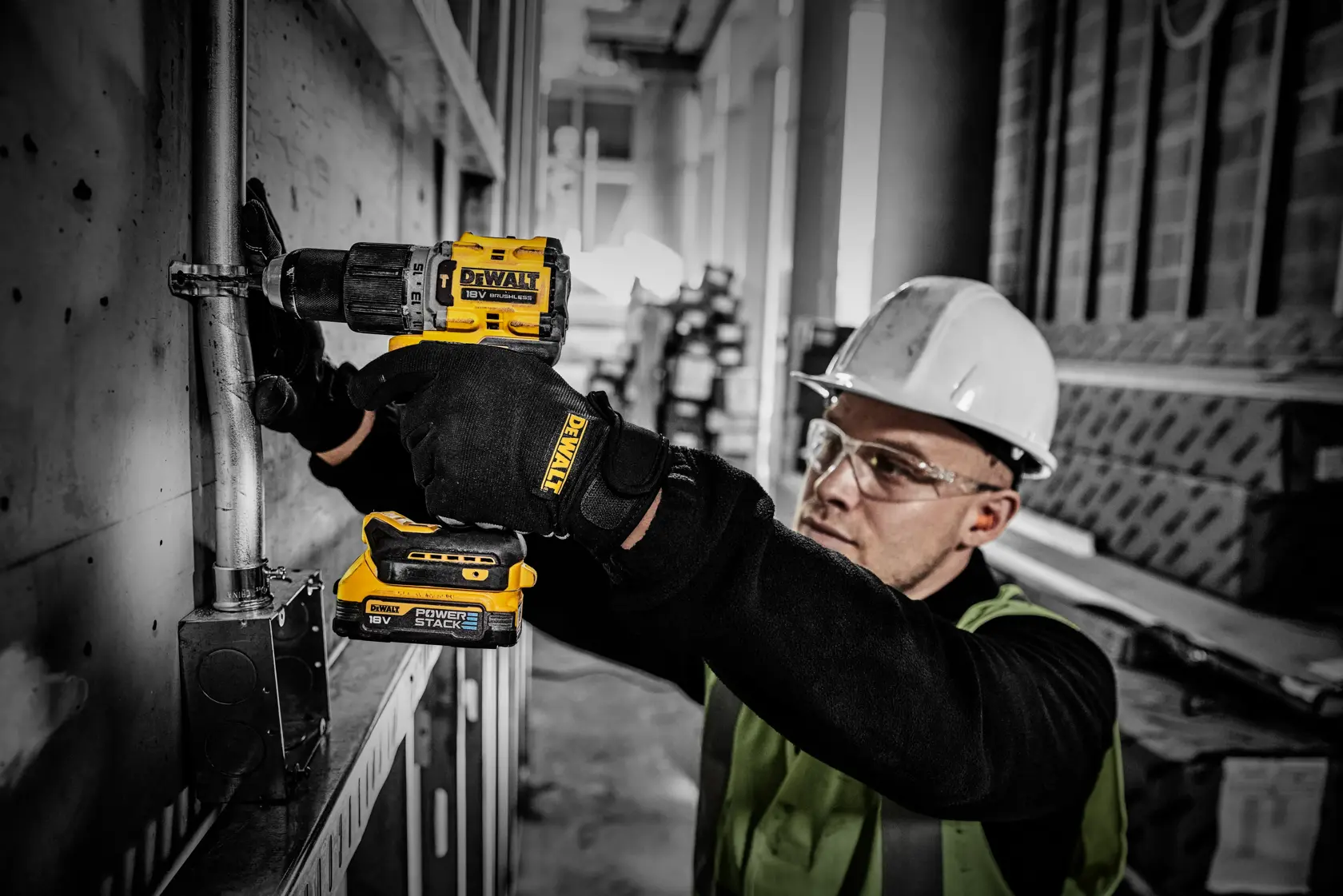 Trabalhador usa bateria DEWALT Powerstack em furadeira sem fio durante instalação elétrica.