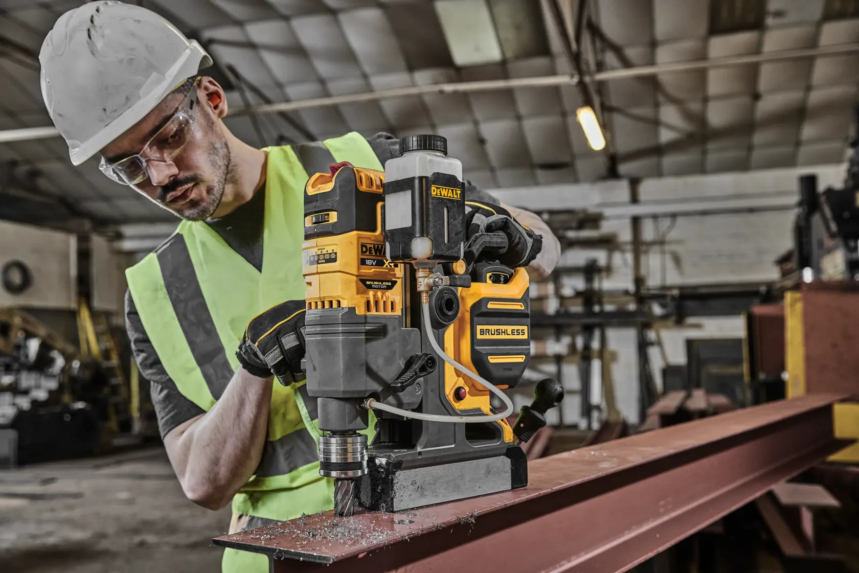Furadeira brushless DEWALT DCD1623N utilizada em viga metálica na oficina, operada por pessoa com EPI.
