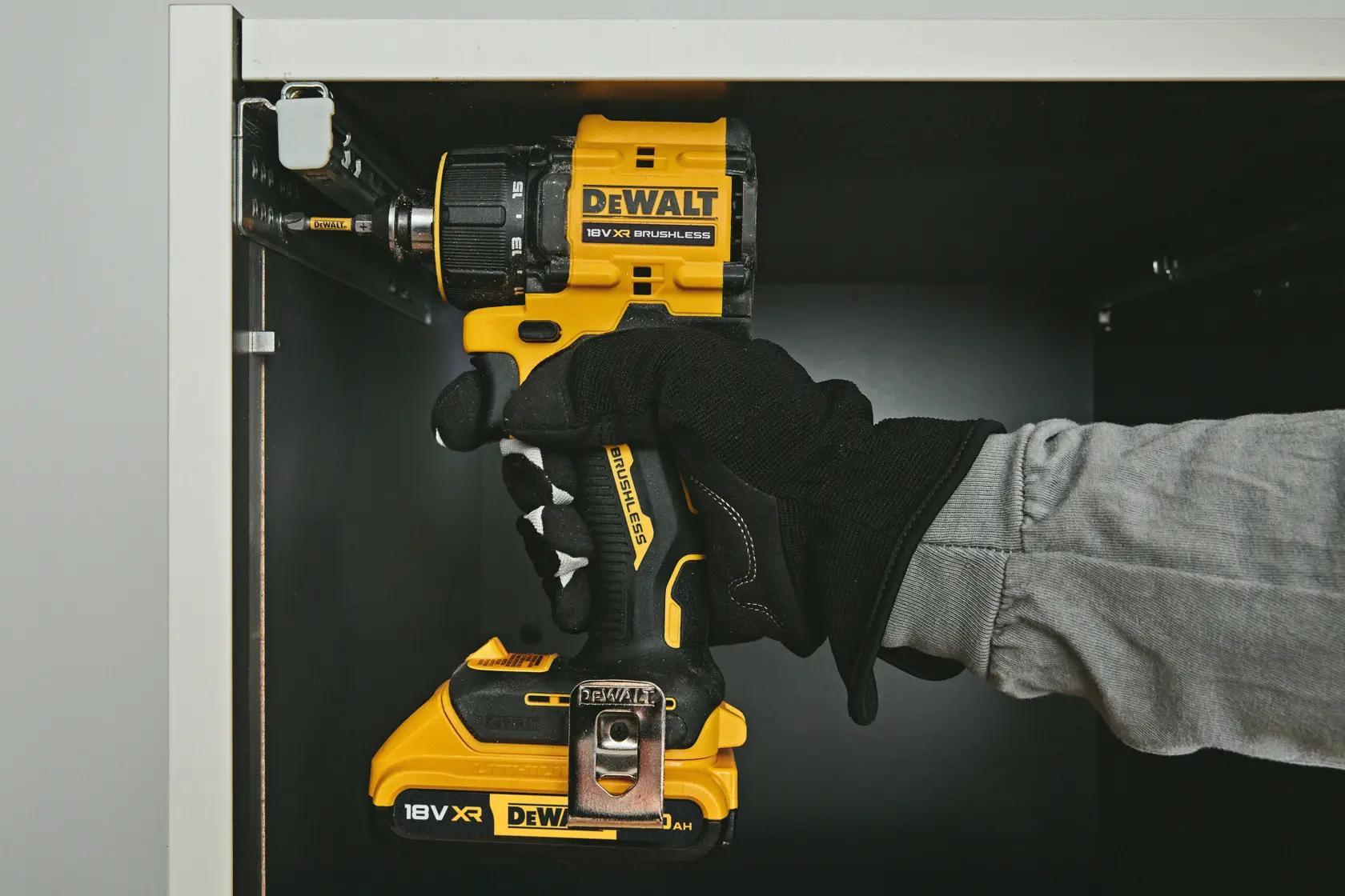 Furadeira DEWALT DCD803NT-XJ, DCD803NT usada em gabinete. Categoria fotografia. Mão com luva visível.