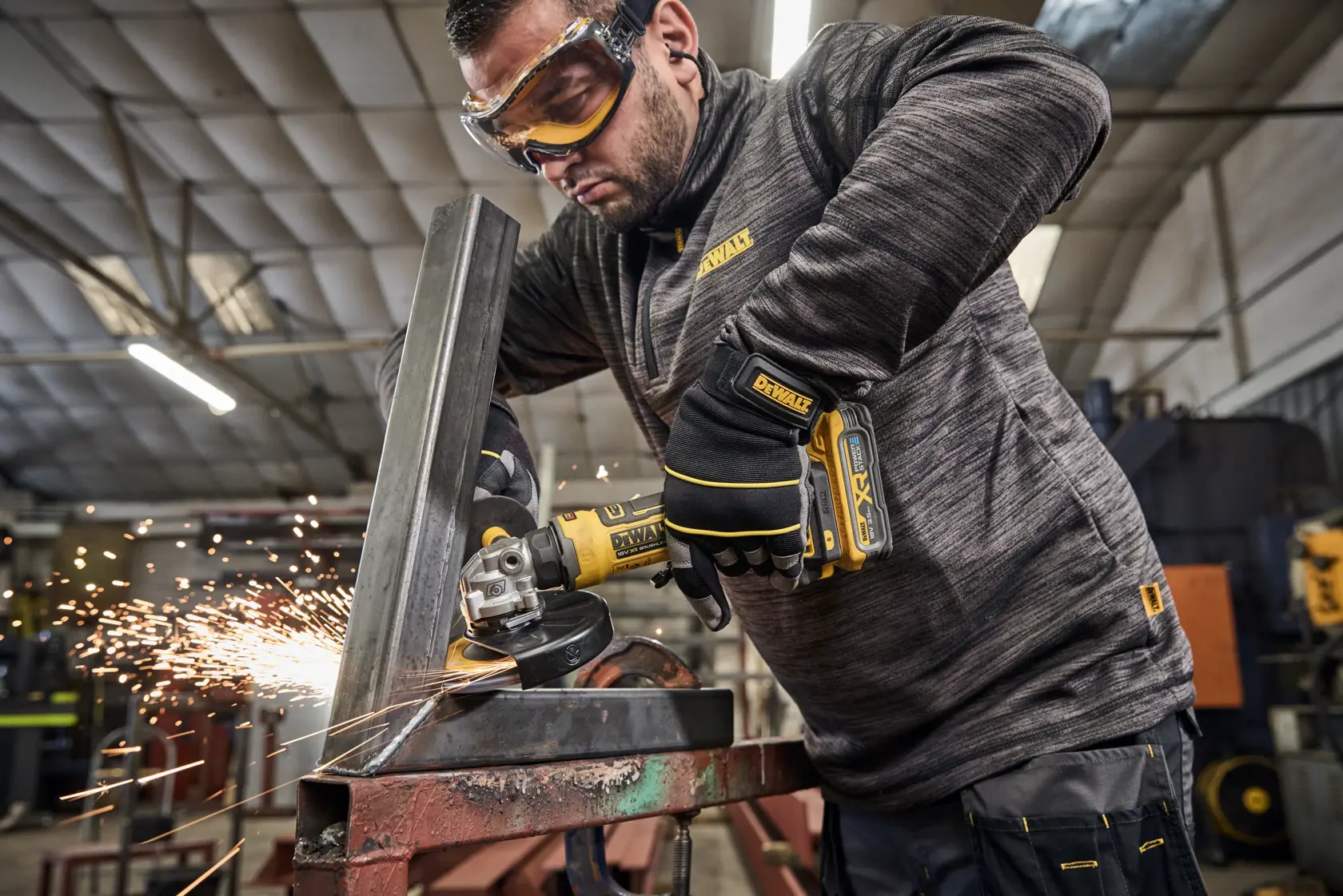 Esmerilhadeira DEWALT cortando metal com faíscas. Operário com luvas em oficina industrial.