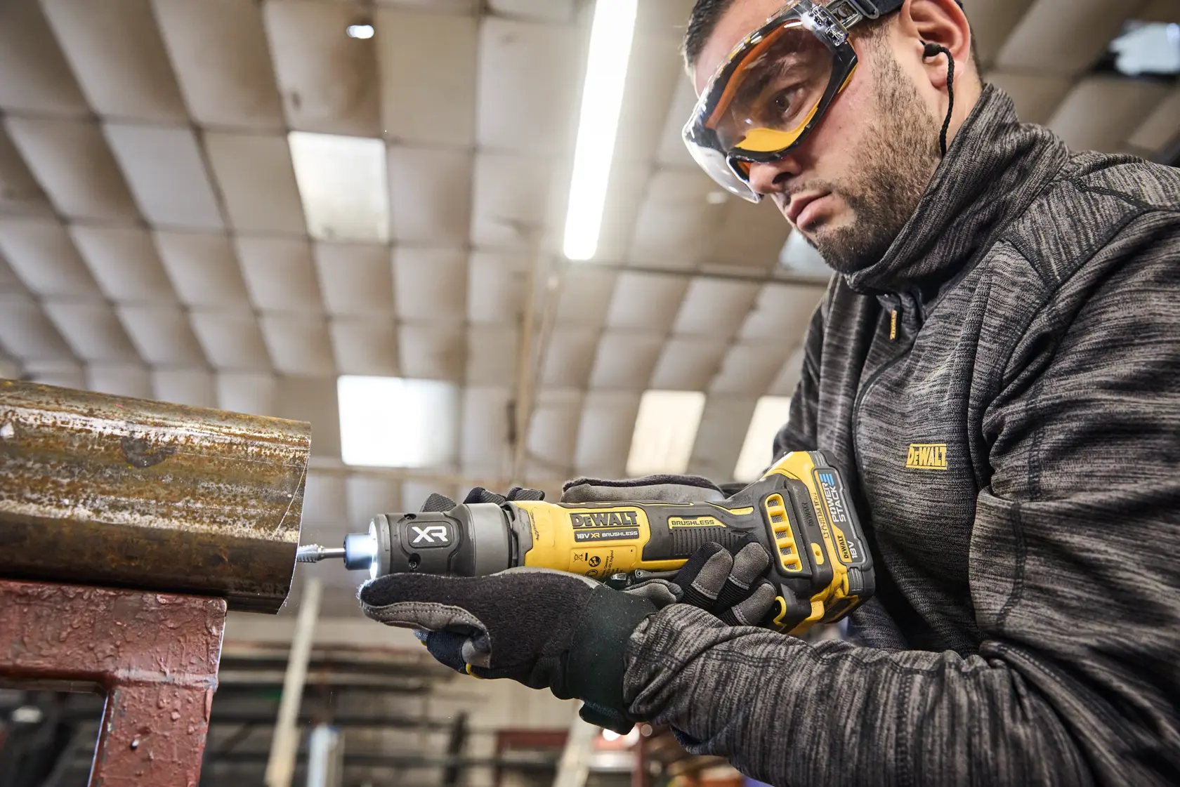 Ferramenta DEWALT DCG420N-XJ, DCG420N em tubo metálico. Usuário com roupa DEWALT. Fotografia.
