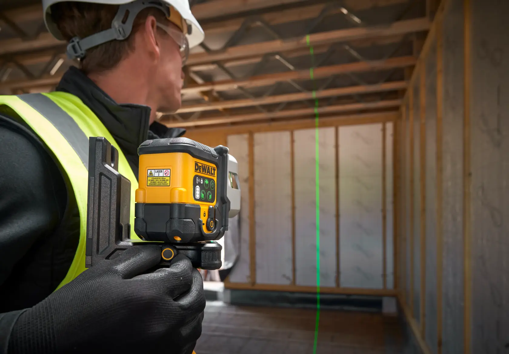 Operário usa nível a laser DEWALT verde para alinhamento em uma construção.