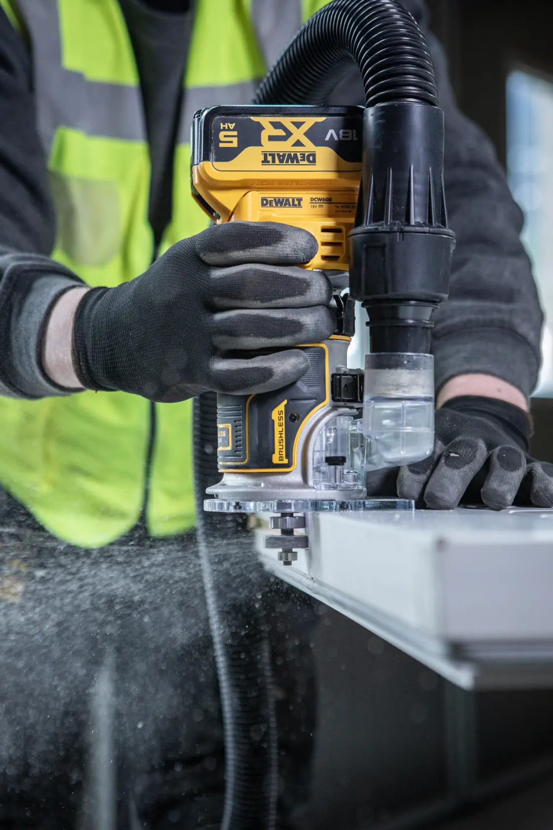 DEWALT DCW604NT-XJ, DCW604NT router en uso con extracción de polvo. Categoría fotografía.