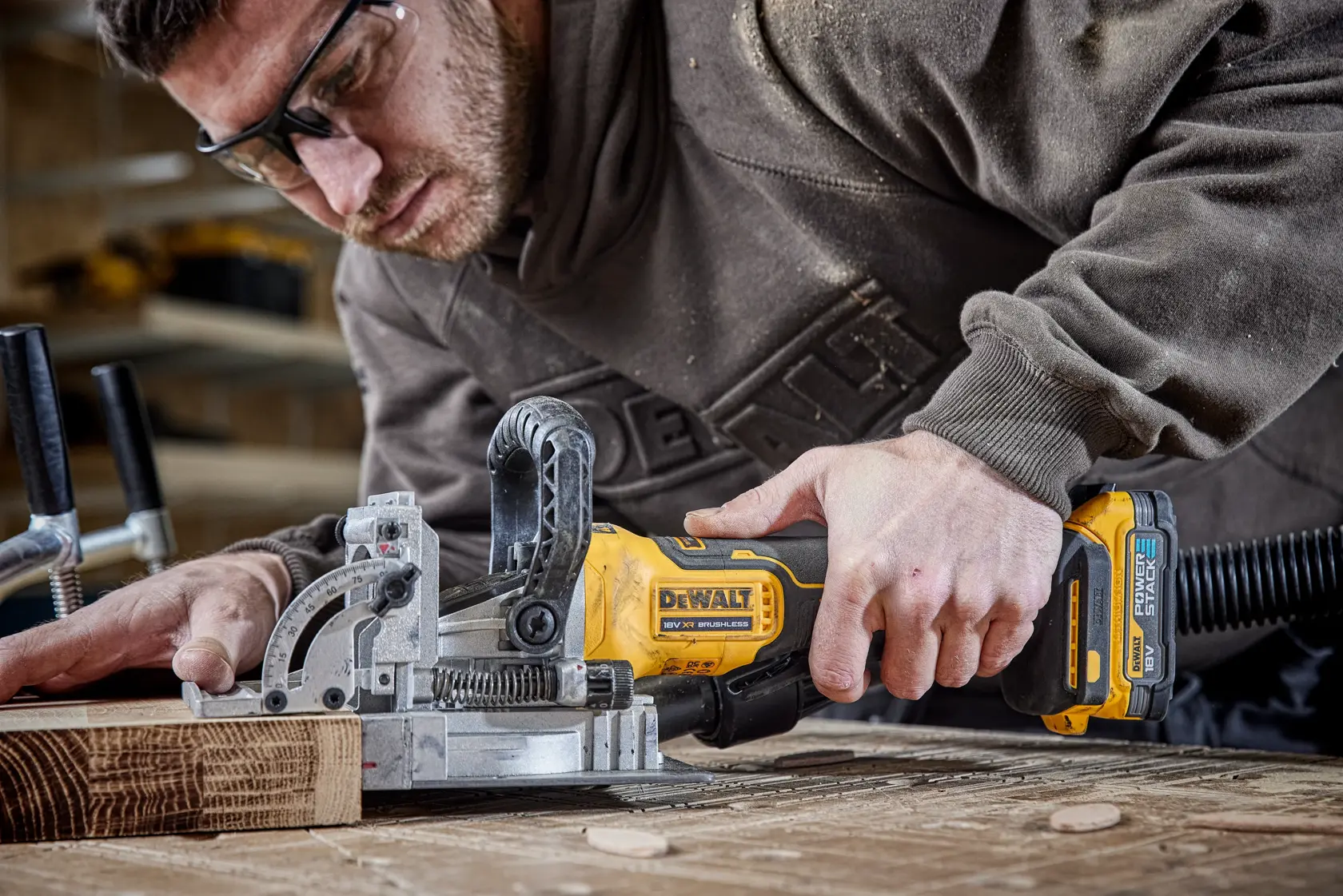 Persona usando una fresadora DEWALT DCW682N inalámbrica para trabajar madera en taller.