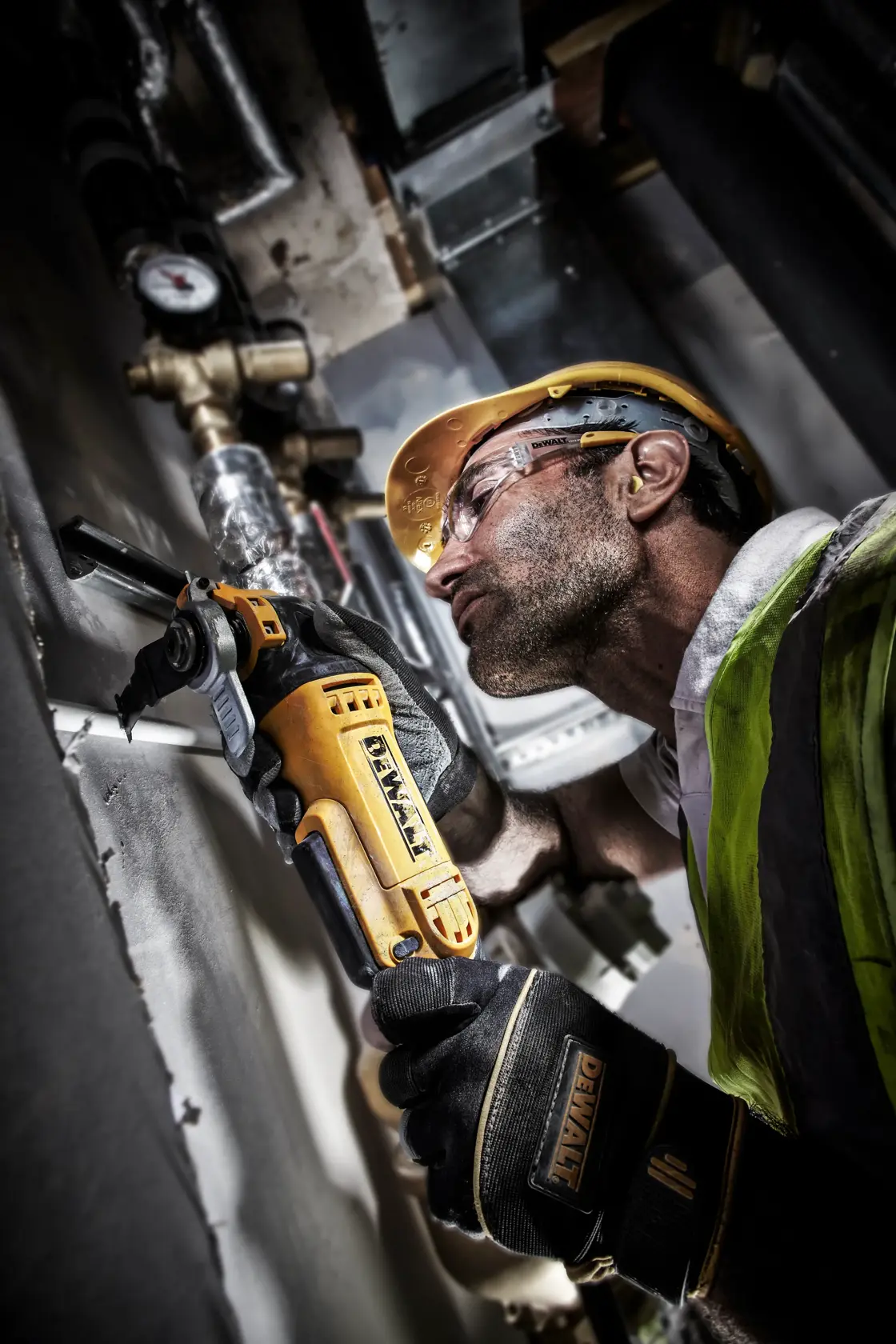 Trabajador con DEWALT DT20701 corta tubería metálica, usando equipo de seguridad en entorno industrial.