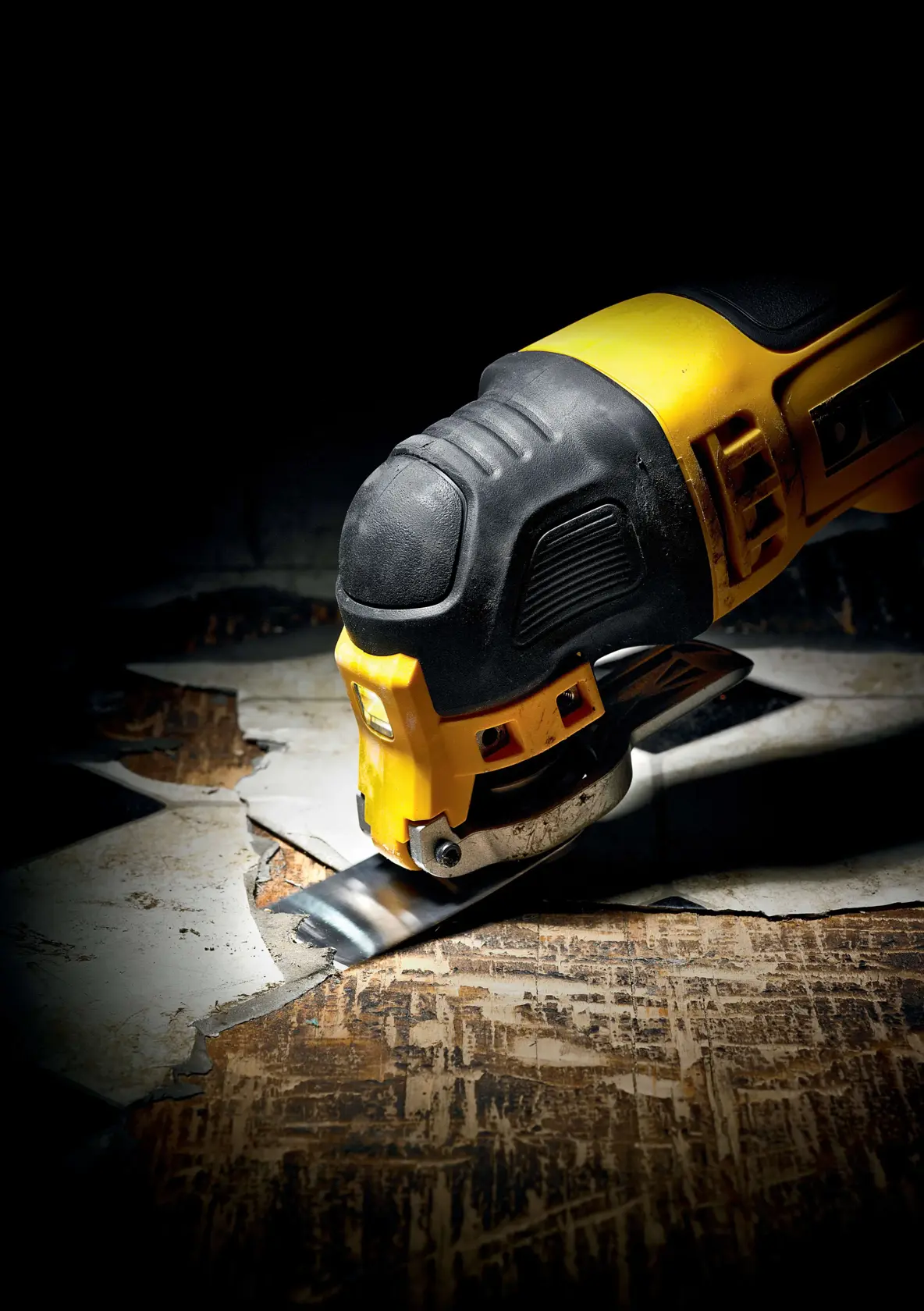 Herramienta oscilante DEWALT cortando suelo viejo, detalle en primer plano de acción y herramienta.