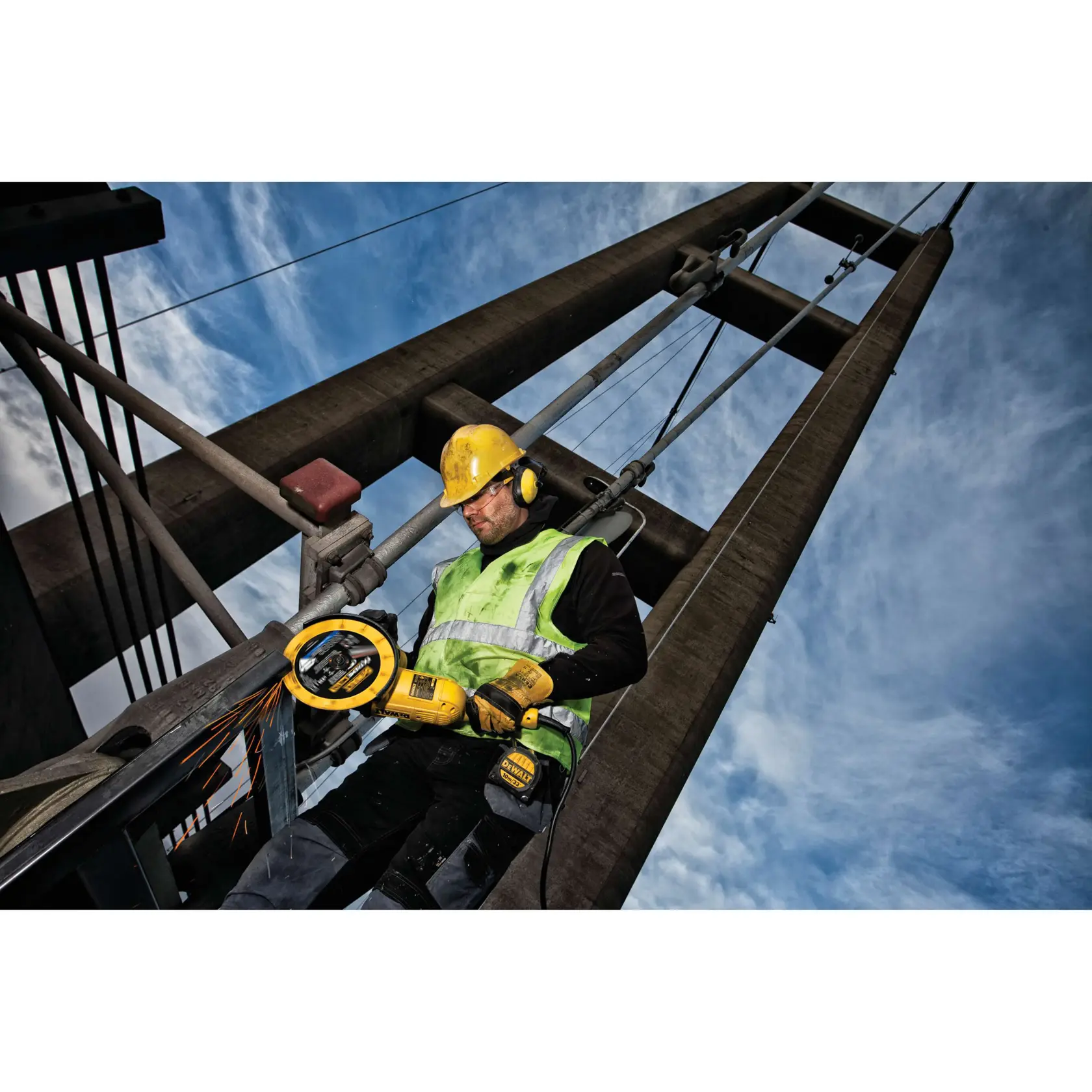 Trabalhador usa ferramenta DEWALT para cortar metal na ponte, com capacete e equipamento de segurança.