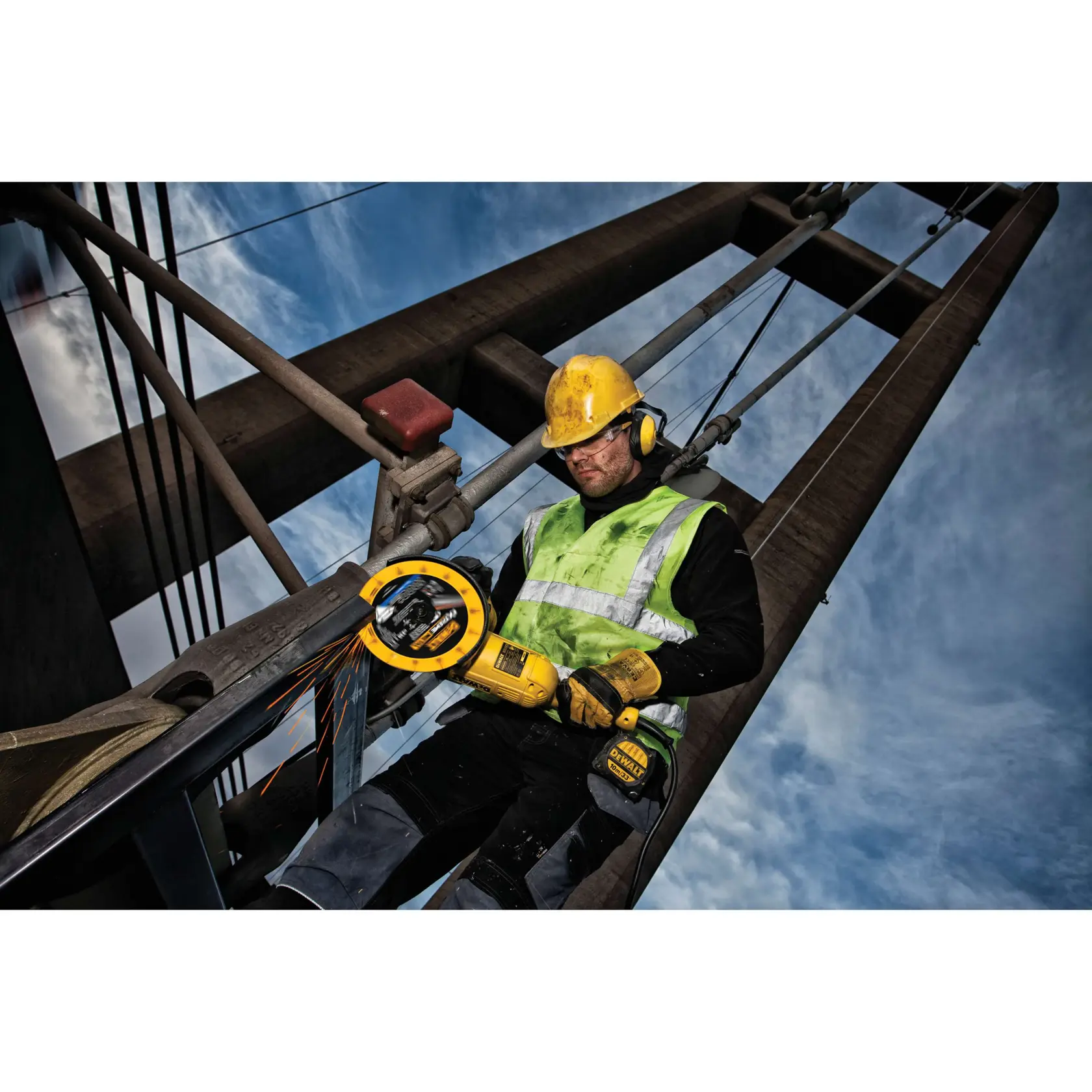 Trabalhador usa esmerilhadeira DEWALT em estrutura metálica ao ar livre com colete refletivo.