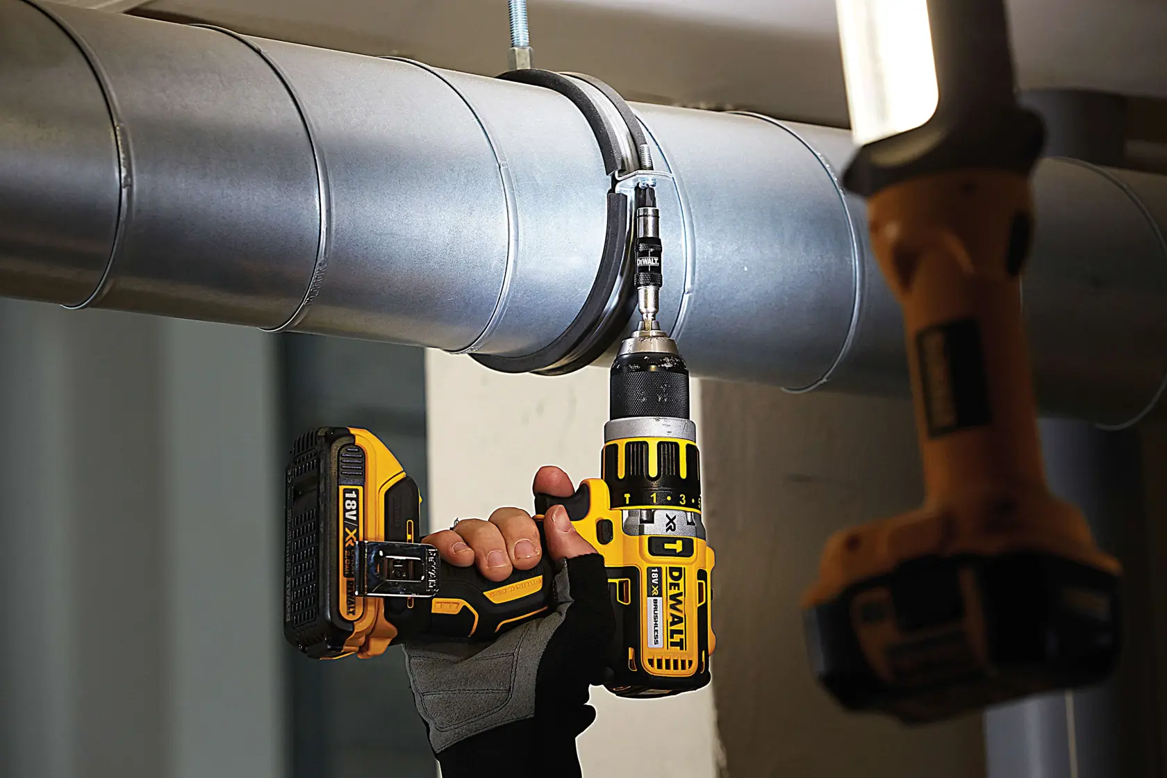 Mano utiliza un taladro inalámbrico DEWALT para fijar un tornillo en una abrazadera de tubo metálico.