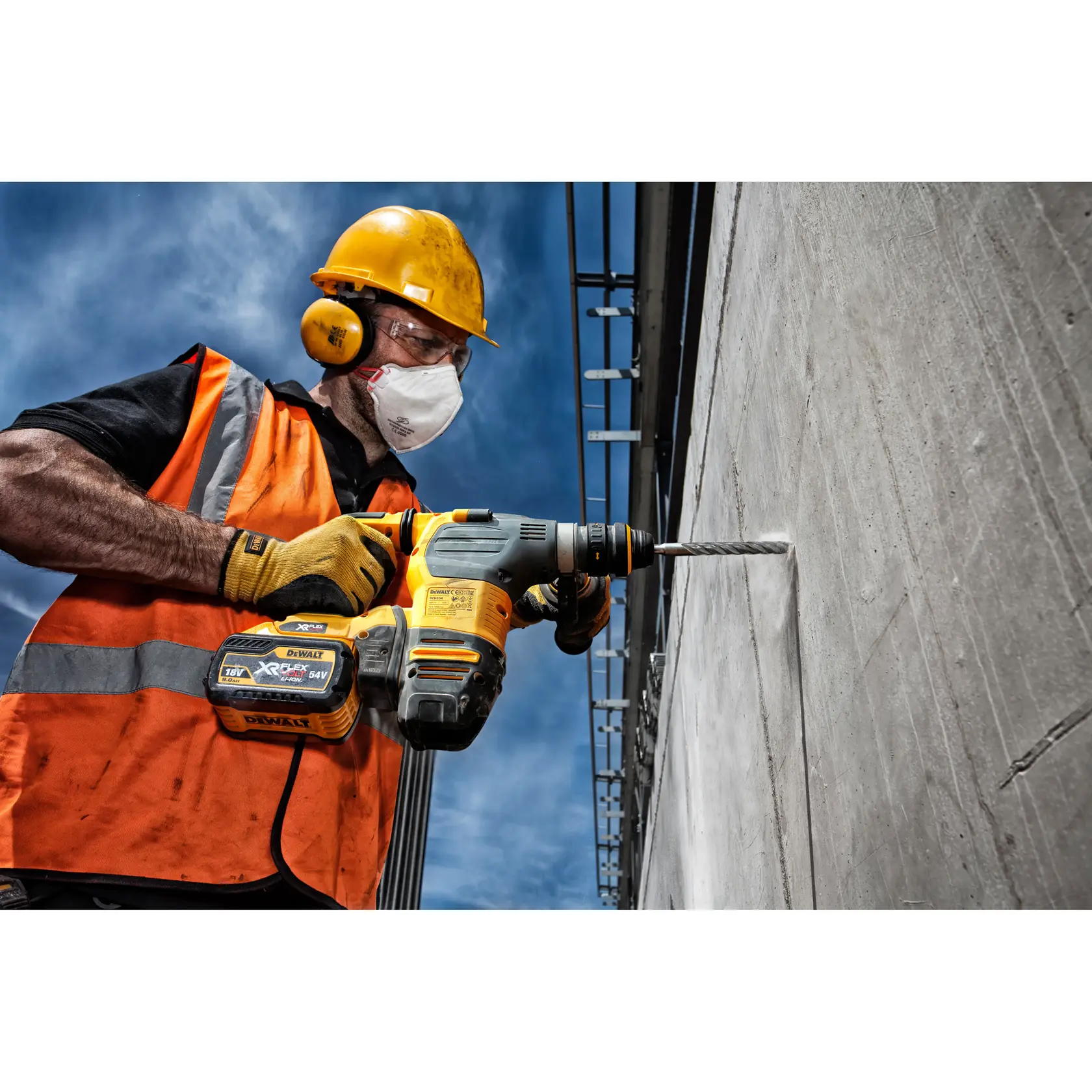Trabajador perfora pared de concreto con DEWALT DT9582, lleva equipo de seguridad afuera.