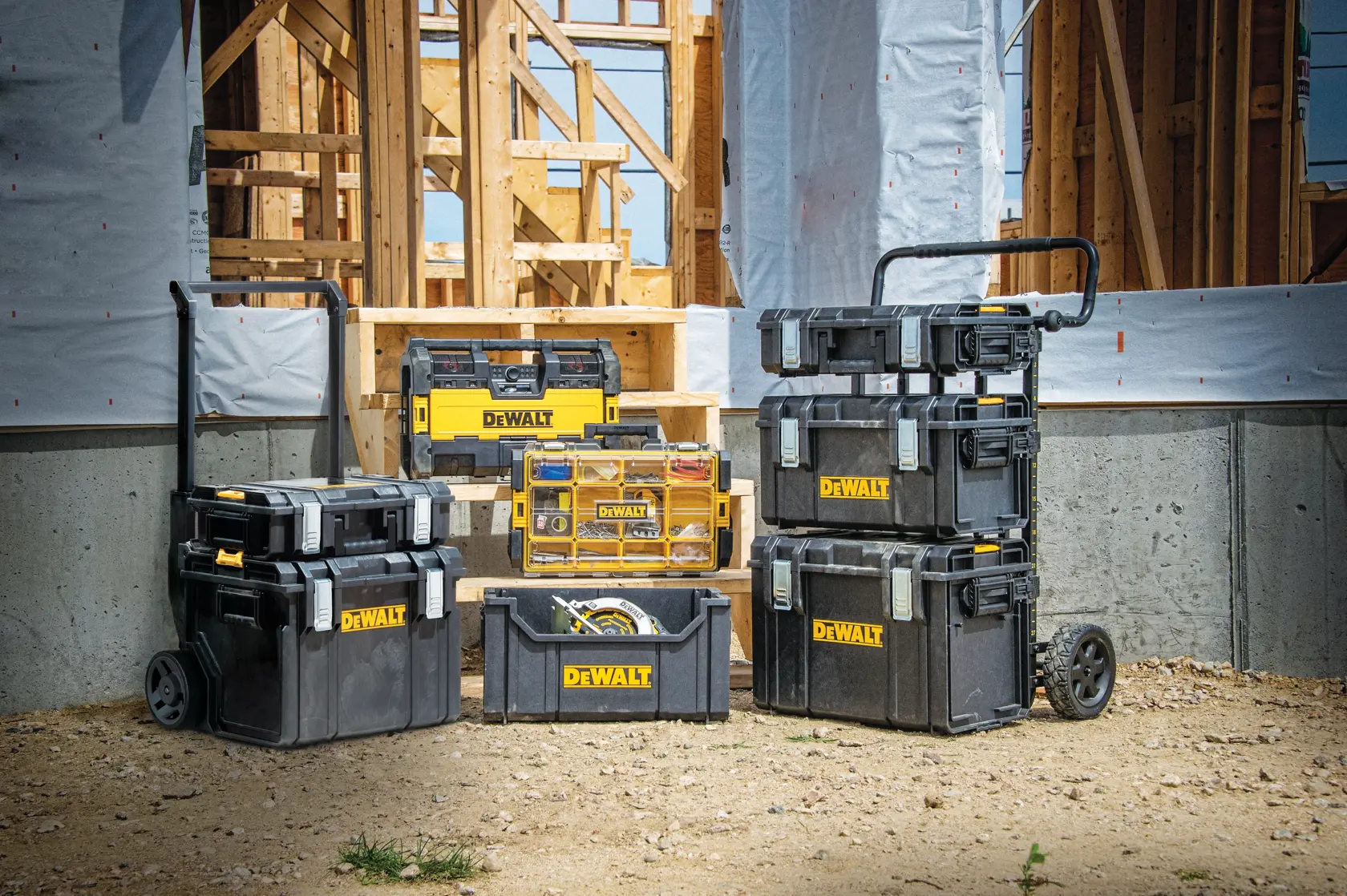 Caixas de ferramentas e organizadores DEWALT em um canteiro de obras com estrutura de madeira ao fundo.