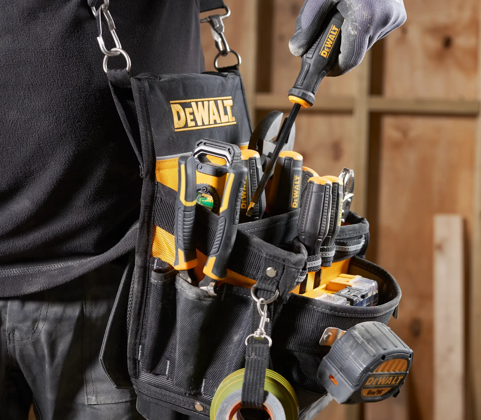 Cinturão de ferramentas DEWALT com ferramentas variadas e trena em uma oficina de carpinteiro.